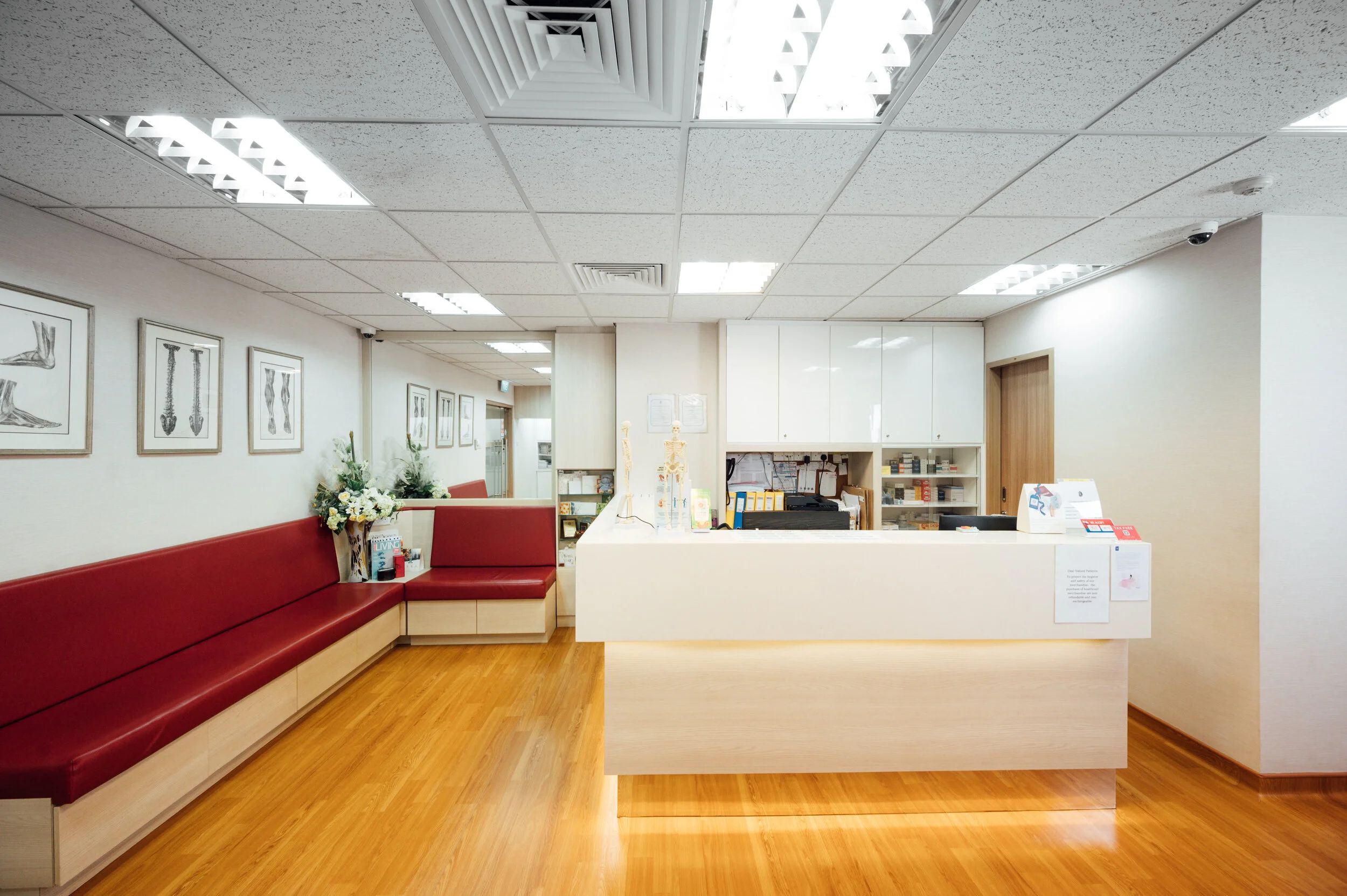 Reception and waiting area at the Orthopaedic and Spine Clinic in Singapore, with anatomical prints on the wall.