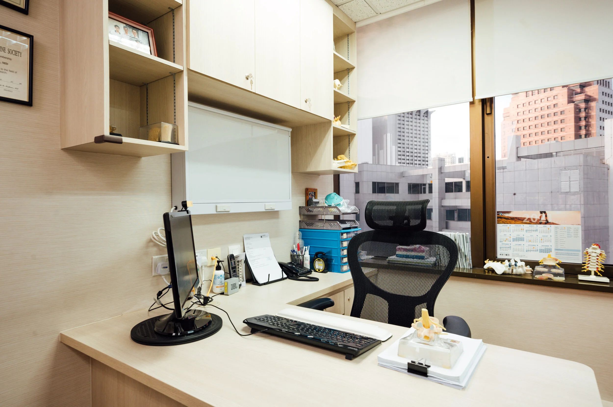 Dr Benjamin Tow's consultation room, with spine models on the windowsill and framed medical credentials.