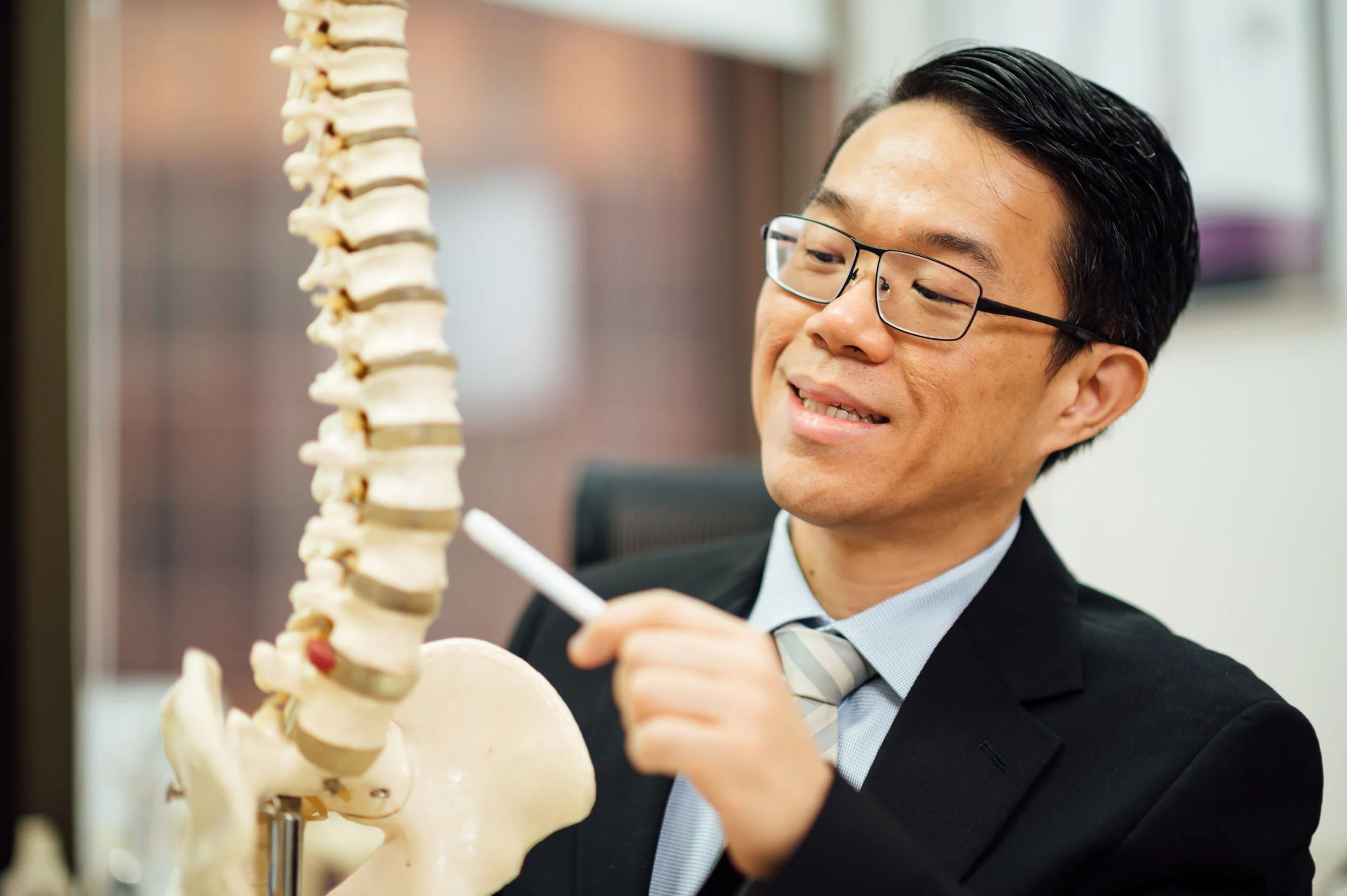 Dr Benjamin Tow using an anatomical spine model to explain a spinal condition.